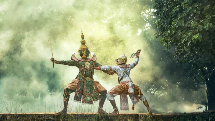 Masked performers in traditional attire strike dynamic poses outdoors amidst a misty backdrop and lush greenery. HD desktop wallpaper and background.