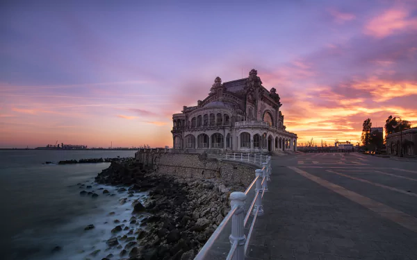 Sunset view of Romania’s historic casino building by the sea, showcasing striking architecture against a colorful sky in this HD desktop wallpaper.