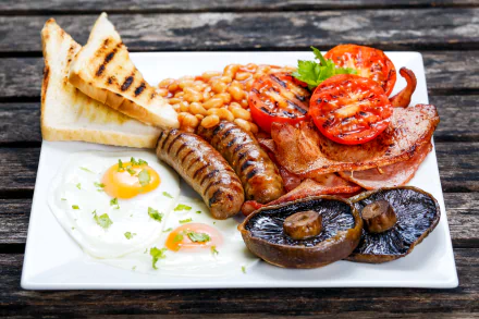 A 4K Ultra HD desktop wallpaper of a full English breakfast featuring beans, toast, bacon, sausage, grilled mushroom, fried eggs, and roasted tomatoes on a white plate.