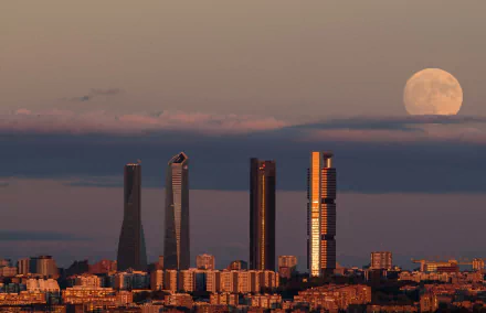 Skyline of Madrid, Spain featuring prominent skyscrapers under a large moon at dusk, captured in an HD cityscape wallpaper.