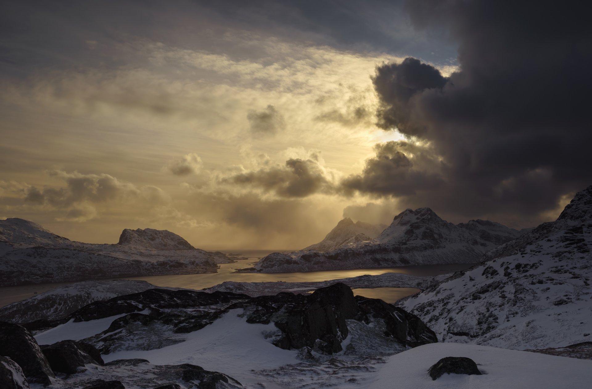 HD image of a dramatic Lofoten landscape, captured through photography, showcasing snow-covered mountains under a moody sky.