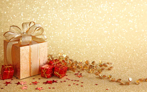 A glittering gold Christmas gift with a satin bow, surrounded by small red presents and festive decorations, presented as a 4K Ultra HD PC desktop wallpaper.