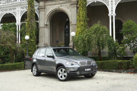 Silver BMW X5 SUV parked in front of an ornate mansion façade, presented as a 4K Ultra HD PC desktop wallpaper background.