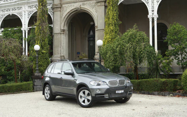 Silver BMW X5 SUV parked in front of an ornate mansion façade, presented as a 4K Ultra HD PC desktop wallpaper background.