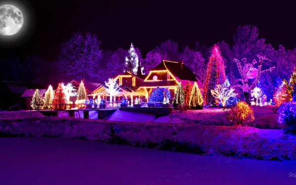 A colorful Christmas house decorated with vibrant holiday lights under a full moon on a snowy winter night, captured as an HD PC desktop wallpaper.