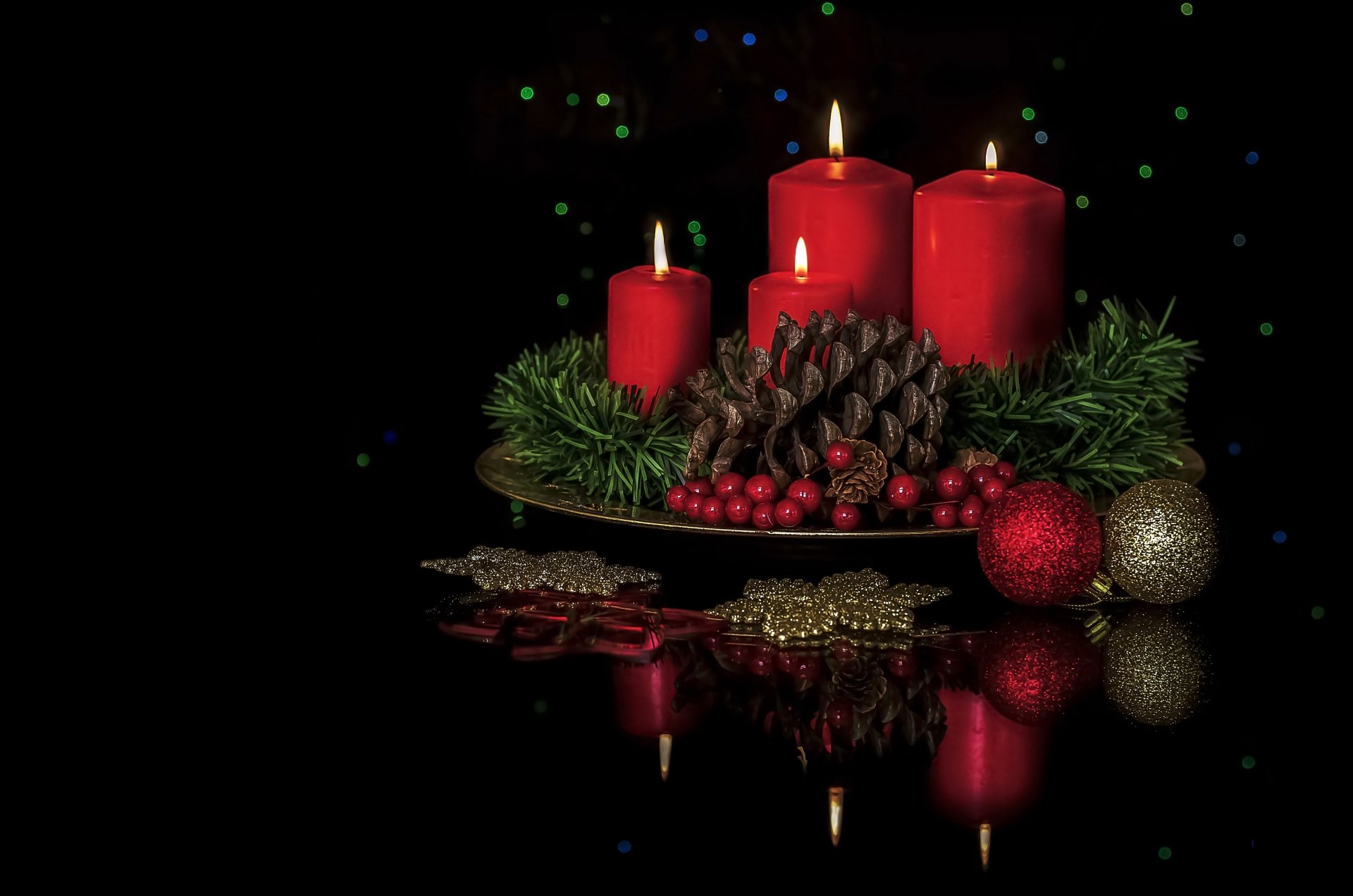 HD wallpaper of a festive arrangement featuring red candles, pine cones, holiday greenery, and Christmas ornaments against a dark background.