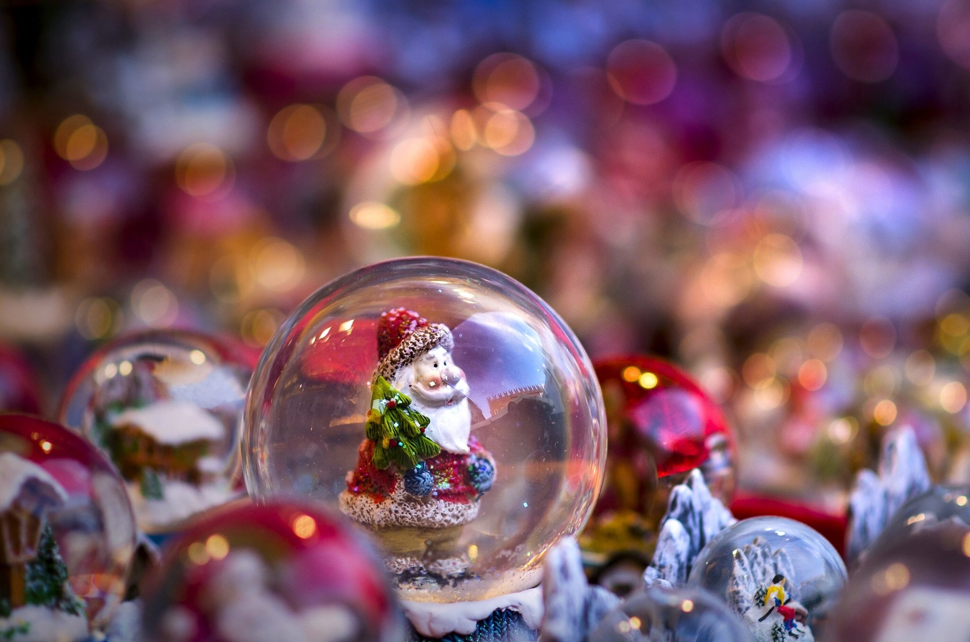 HD PC desktop wallpaper featuring a festive Santa inside a snow globe with colorful holiday bokeh lights creating a warm Christmas atmosphere.