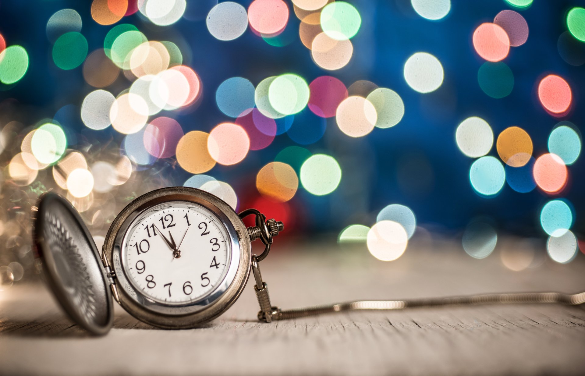 5K Ultra HD PC desktop wallpaper background: antique pocket watch on a wooden surface with colorful holiday bokeh lights evoking a New Year countdown.