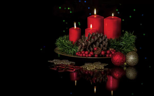HD wallpaper of a festive arrangement featuring red candles, pine cones, holiday greenery, and Christmas ornaments against a dark background.