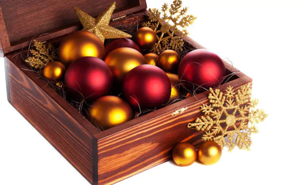 2K Quad HD desktop wallpaper: wooden box filled with red and gold Christmas ornaments, golden star and glitter snowflake holiday decorations on white background.