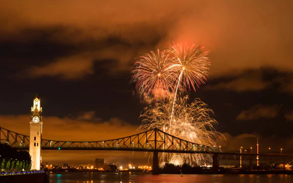 4K Ultra HD wallpaper of Montreal's illuminated bridge over a river at night with vibrant orange fireworks lighting up the sky in Canada.