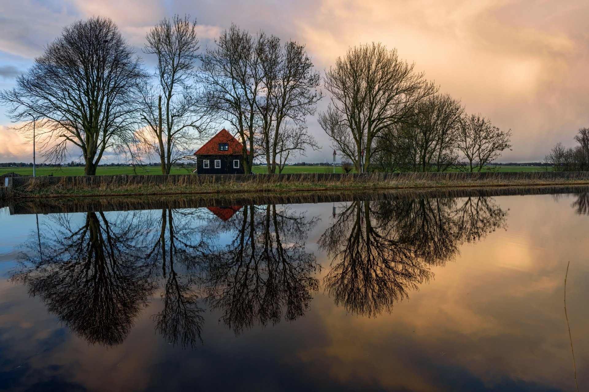 HD desktop wallpaper featuring a house and tree-lined shore reflected in a calm lake, epitomizing serene photography.