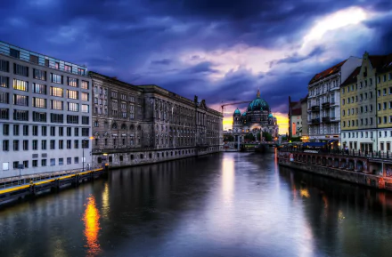 Dusk over the river in Berlin, featuring the illuminated Berlin Cathedral and surrounding man-made buildings reflected on the water in this HD desktop wallpaper.