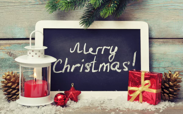 A festive holiday scene with Merry Christmas! written on a chalkboard, surrounded by pinecones, a red candle lantern, ornaments, and a gift, captured in 8K Ultra HD for PC desktop.
