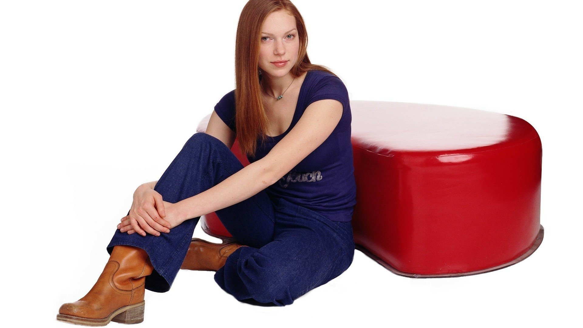 HD PC desktop wallpaper featuring Laura Prepon from the TV show That '70s Show, sitting casually beside a glossy red cube.
