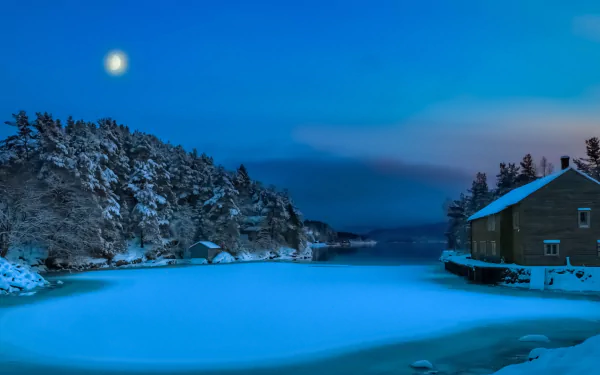 Winter night scene in Norway with snow-covered trees, a frozen bay, a bright moon, and a man-made house, captured in high definition for a PC desktop wallpaper.