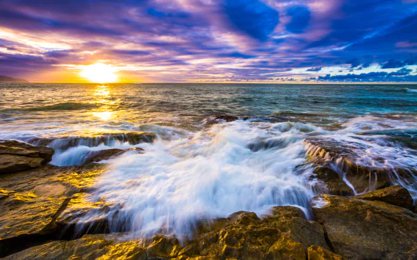 A vibrant 4K Ultra HD wallpaper capturing a Hawaiian ocean sunset with waves crashing over rocky shores beneath a colorful sky on the horizon.