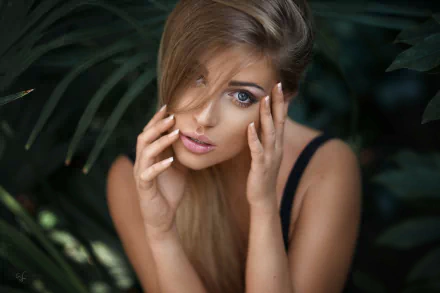 HD desktop wallpaper featuring a close-up of blonde model Lina Roth’s face framed by dark foliage, highlighting her striking blue eyes and natural beauty.