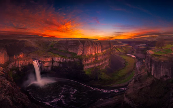 A stunning HD desktop wallpaper featuring Palouse Falls in Washington, captured at sunset. The landscape showcases a dramatic waterfall cascading into the canyon, with vibrant colors illuminating the sky.