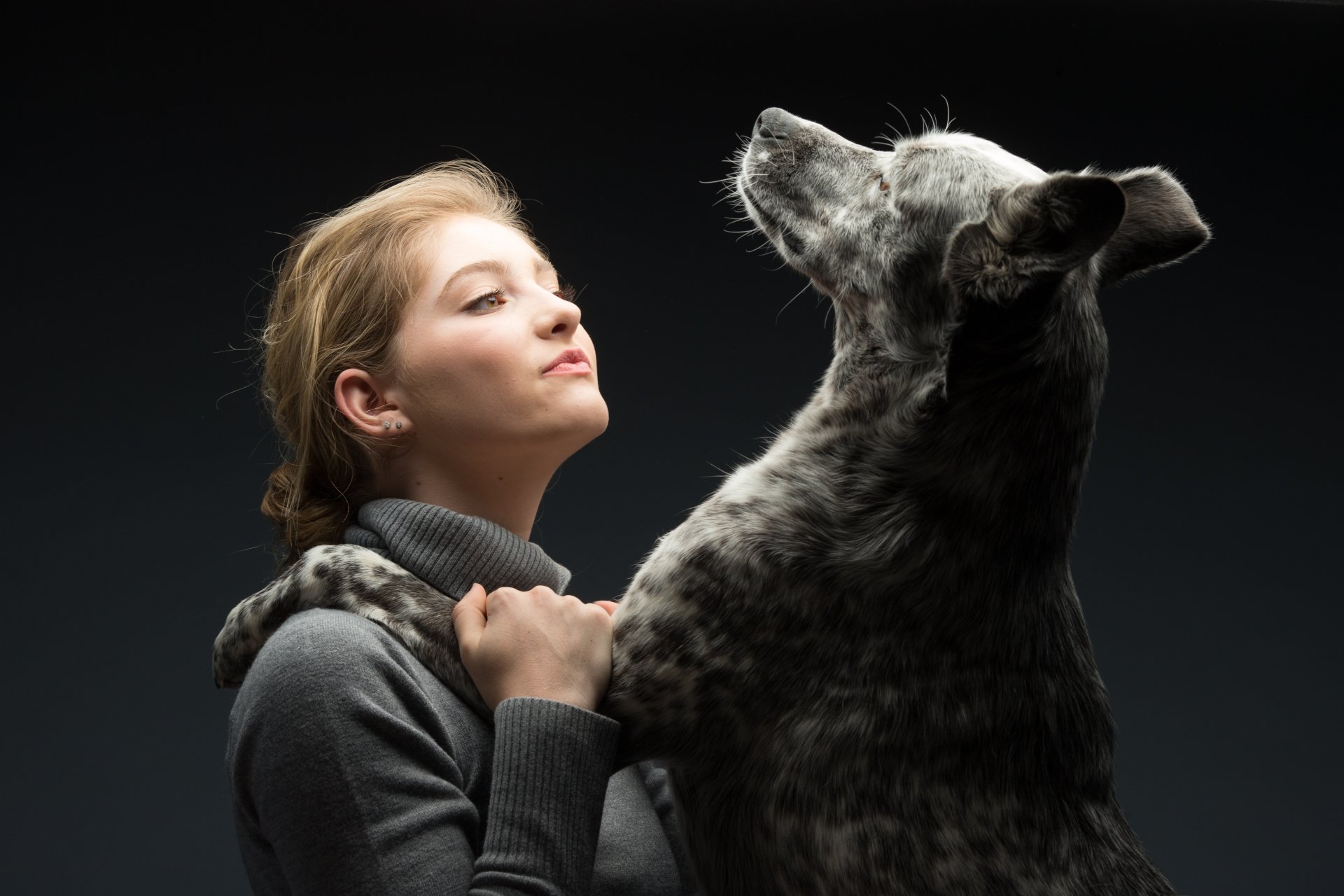 Blonde American actress Willow Shields embraces a large dog with brown eyes against a dark background in this 4K Ultra HD PC desktop wallpaper.