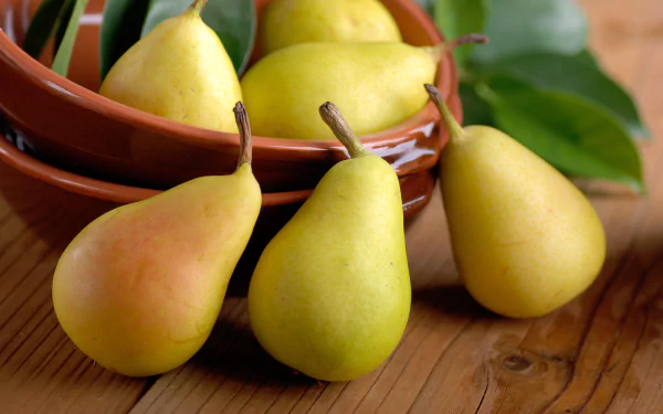 A 4K Ultra HD PC desktop wallpaper featuring fresh yellow pears arranged on and around stacked brown bowls with green leaves and a wooden surface background.