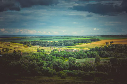 4K Ultra HD landscape of a Russian countryside featuring a green forest, expansive fields, a village, and a cloudy sky stretching along the horizon.