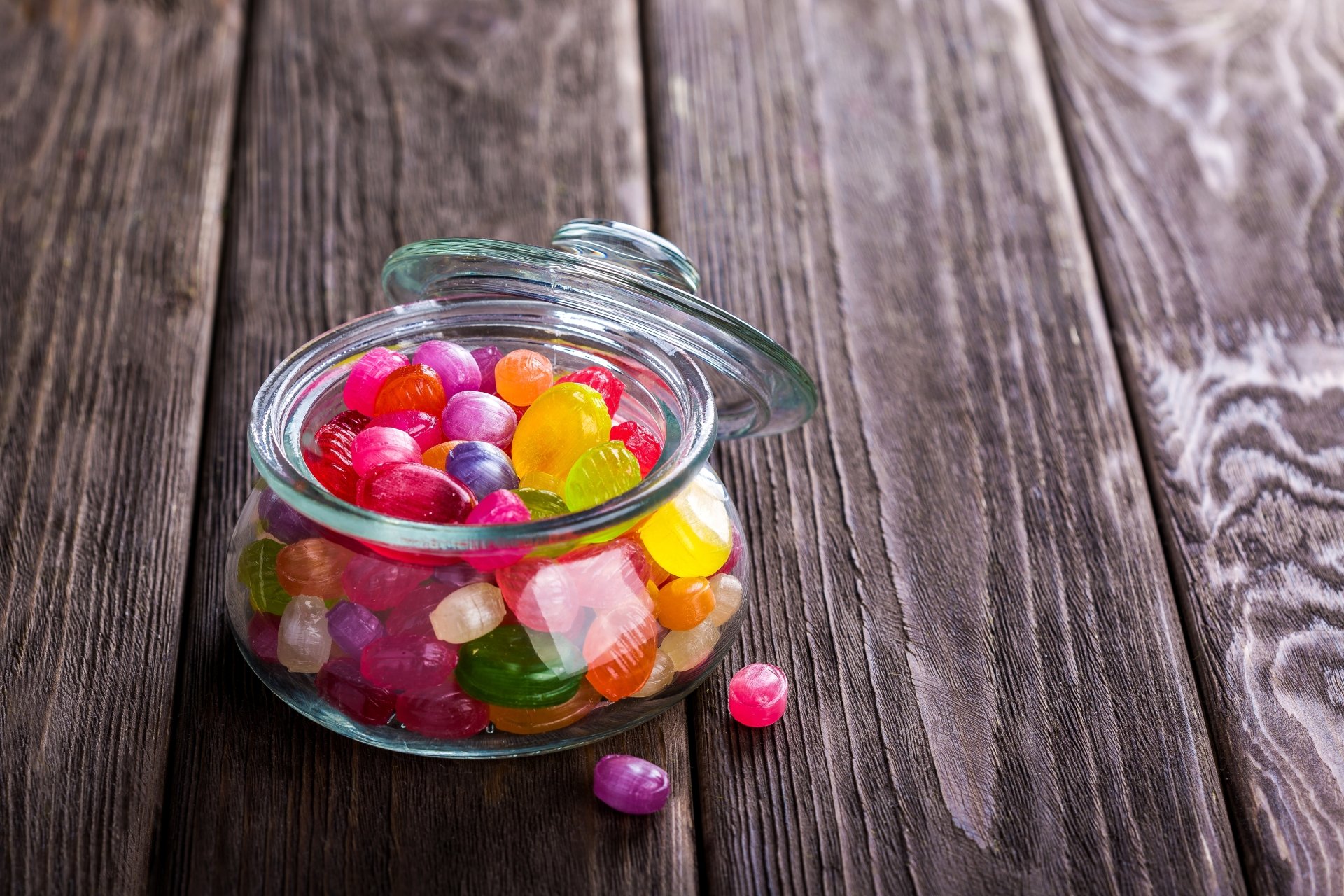 A vibrant jar filled with colorful sweets and candies on a rustic wooden surface, captured in sharp 4K Ultra HD quality as a PC desktop wallpaper background.