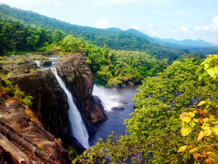 HD desktop wallpaper showcasing Athirappilly Falls cascading through lush greenery in India, surrounded by vibrant nature and forested hills.