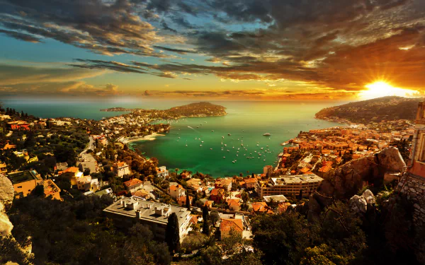 Panoramic 4K Ultra HD view of Saint-Jean-Cap-Ferrat and Villefranche-sur-Mer coastline at sunset, featuring boats on the sea and a vibrant ocean horizon in France.