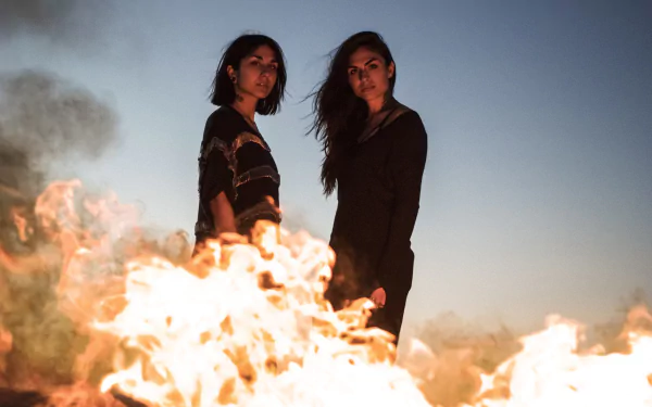 HD PC desktop wallpaper featuring Krewella standing behind a blazing fire under a clear sky, capturing a dramatic and intense music-themed scene.