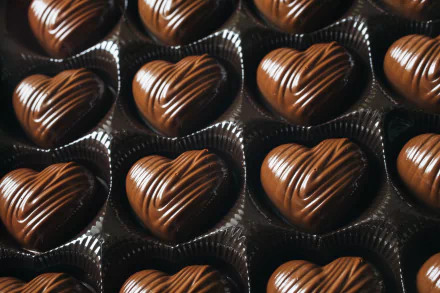 HD desktop wallpaper featuring a close-up of heart-shaped chocolates arranged in neat rows, highlighting their glossy texture and fine detailing.