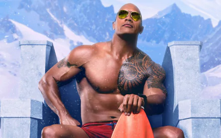 Dwayne Johnson in a Baywatch movie-themed HD desktop wallpaper, seated in front of snowy mountains, wearing sunglasses and holding a lifeguard floatation device.