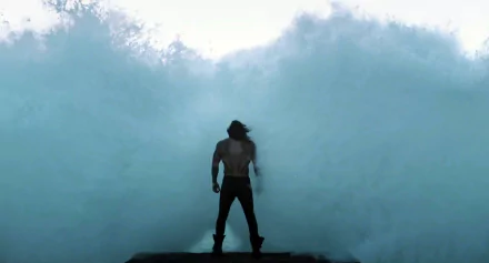 Arthur Curry, portrayed by Jason Momoa as Aquaman, stands facing the sea with waves crashing, capturing a powerful superhero moment from the Justice League movie.
