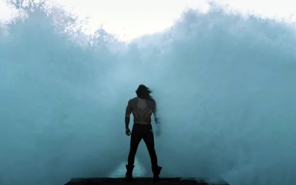 Arthur Curry, portrayed by Jason Momoa as Aquaman, stands facing the sea with waves crashing, capturing a powerful superhero moment from the Justice League movie.