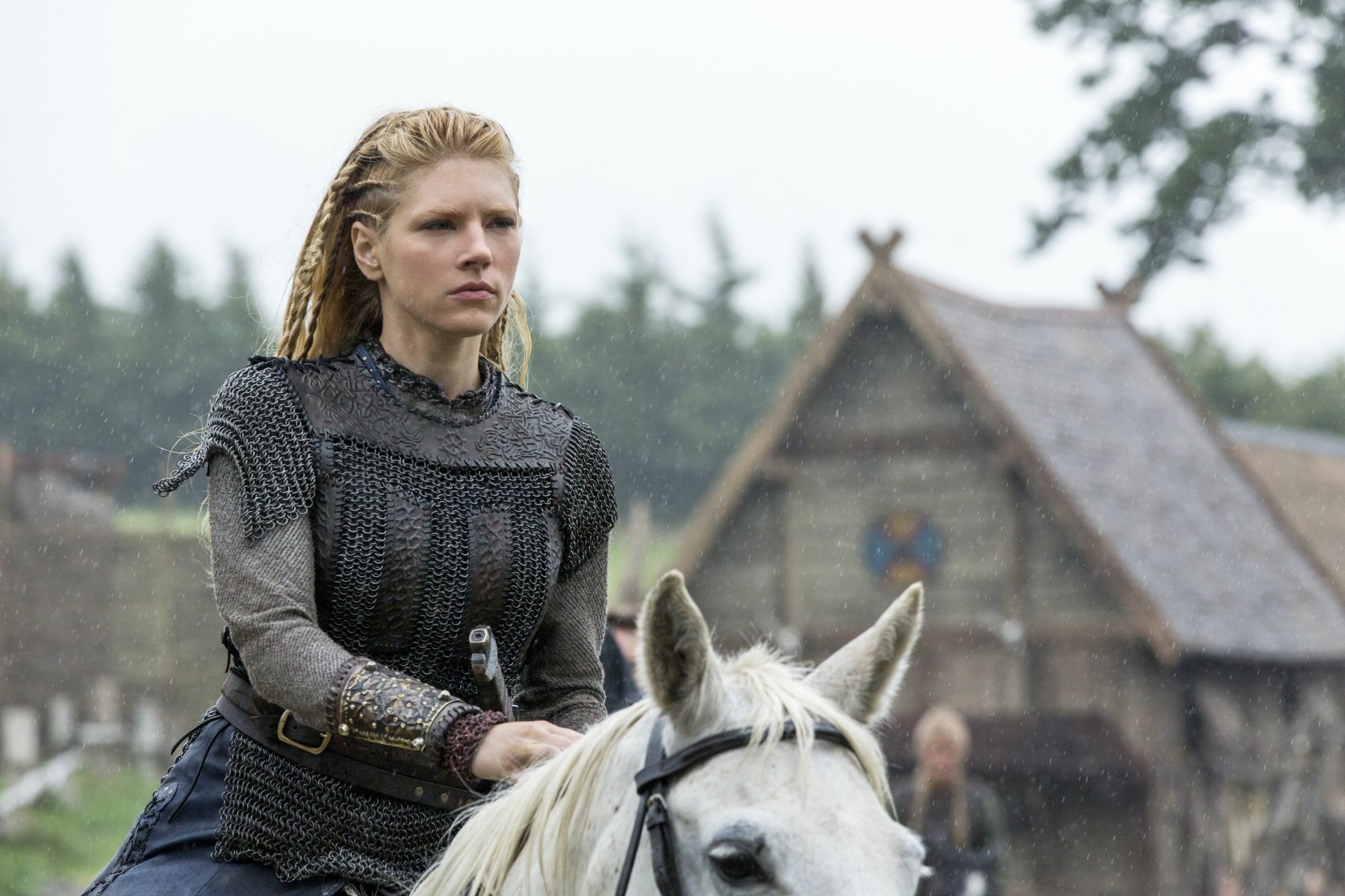 Blonde shieldmaiden in chainmail on a white horse in a Viking village, scene from Vikings (2013) TV show — 5K Ultra HD desktop wallpaper.