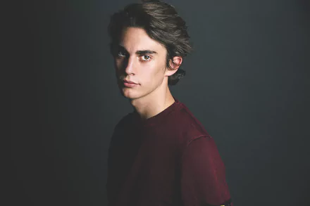 5K Ultra HD PC desktop wallpaper: head-and-shoulders portrait of a male model with brown eyes in a burgundy shirt against a dark, moody background.