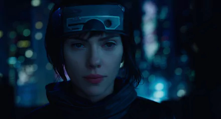 HD desktop wallpaper featuring Scarlett Johansson from the movie Ghost in the Shell (2017), with a futuristic cityscape background and Johansson in character wearing a headband and jacket.