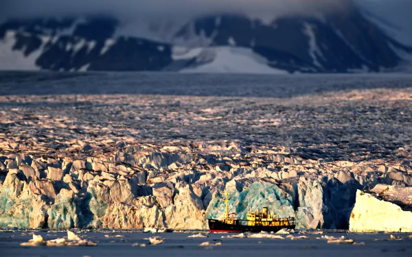 HD desktop wallpaper featuring a tilt-shift photography of a boat sailing near a massive iceberg with a snowy mountain backdrop.