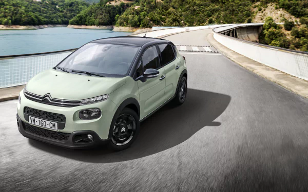 Citroën C3 compact car on a winding mountain road, depicted as a 2K Quad HD PC desktop wallpaper background.