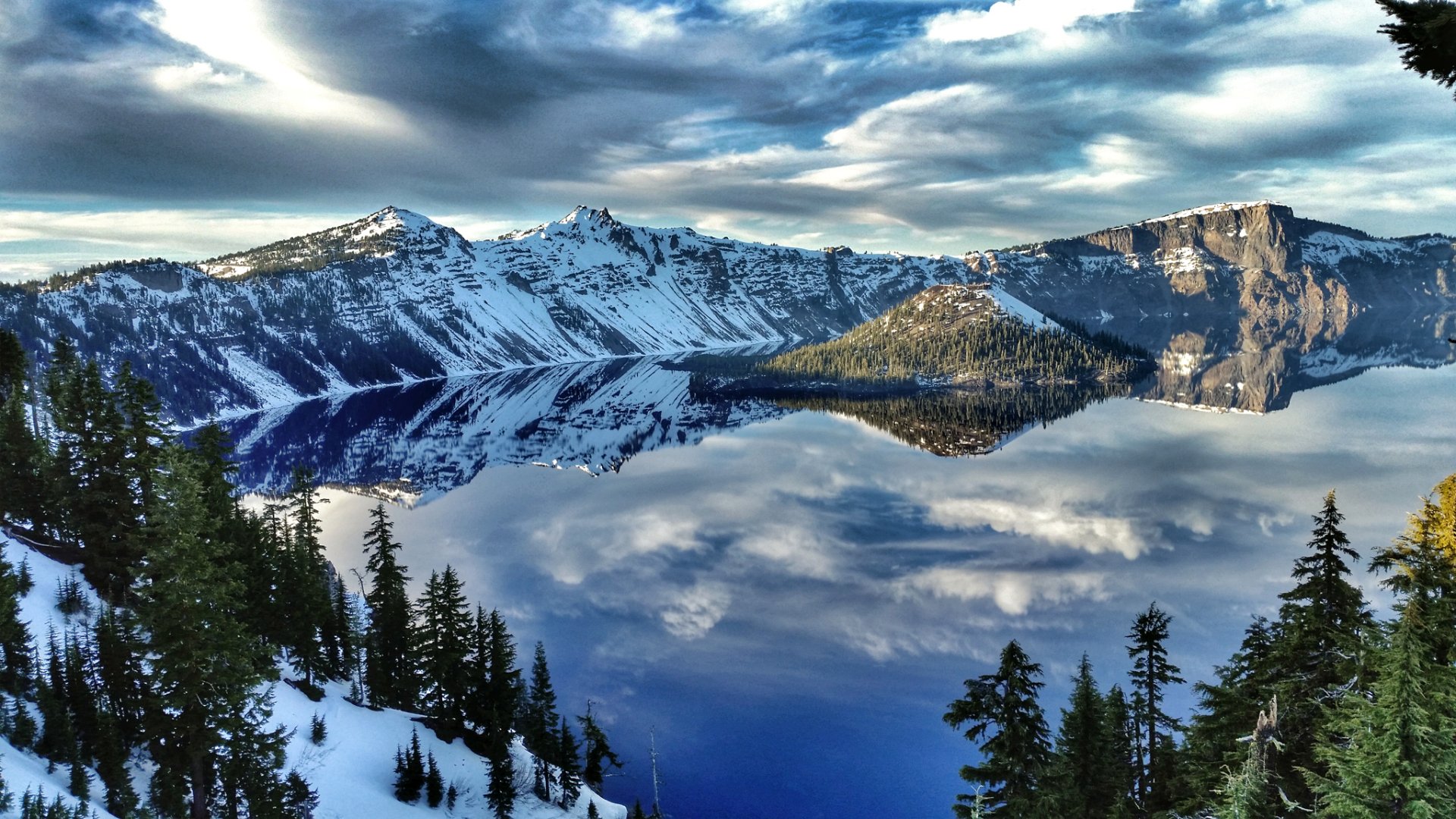 HD desktop wallpaper of Crater Lake reflecting clouds and surrounding snow-covered island and mountains in clear, serene nature scene.