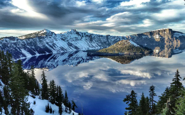 HD desktop wallpaper of Crater Lake reflecting clouds and surrounding snow-covered island and mountains in clear, serene nature scene.