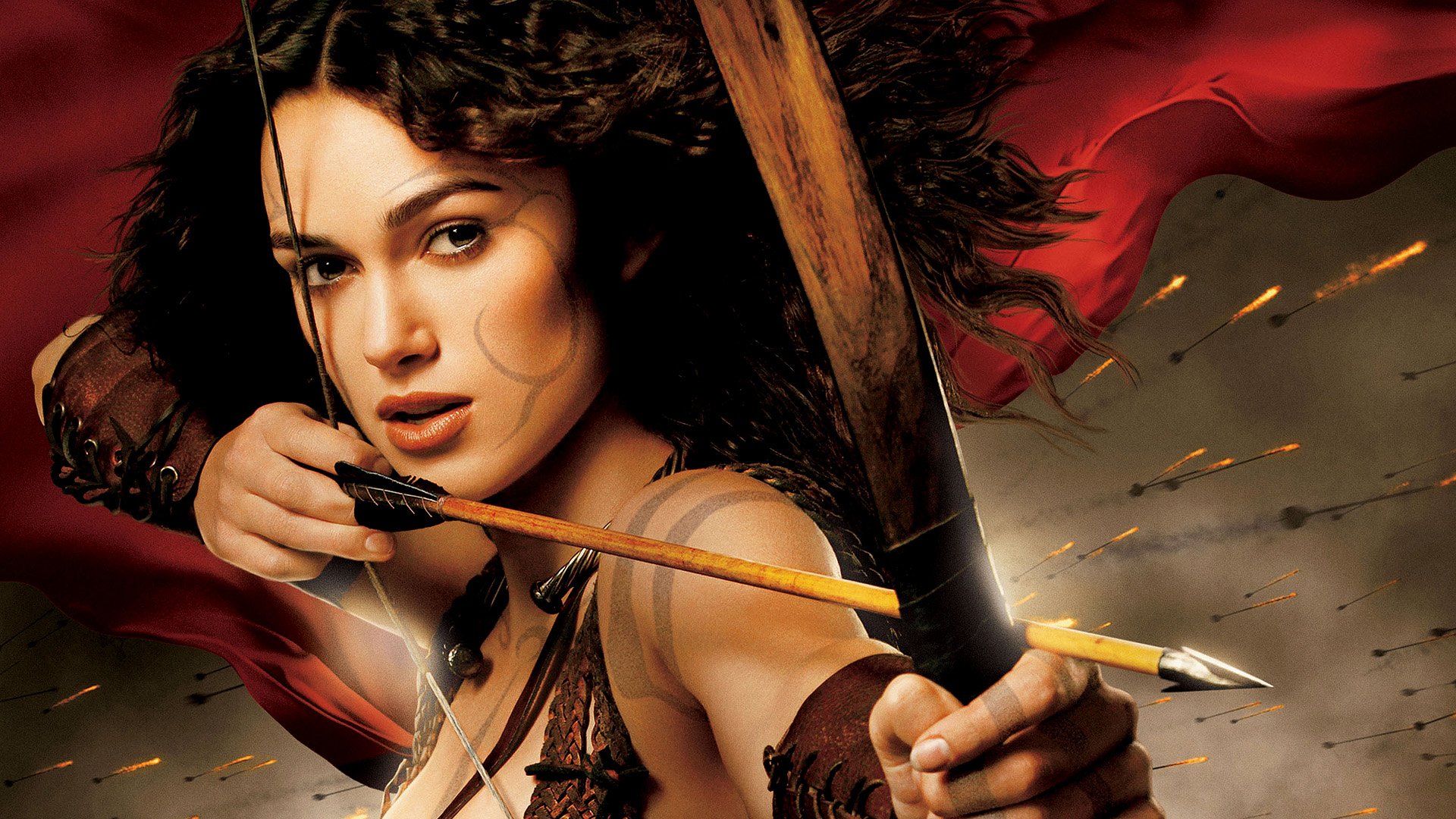 HD PC desktop wallpaper featuring a dramatic close-up of a female archer from the movie King Arthur, with intense expression and a backdrop of red fabric and arrows in flight.