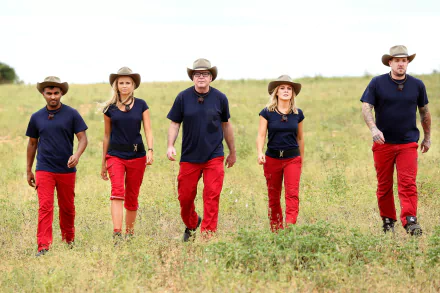 Australian cast of I'm a Celebrity: Get Me Out of Here! (AU) including Dane Swan, Natalie Bassingthwaighte, Tom Arnold, Tegan Martin, and Nazeem Hussain walking through a grassy field.