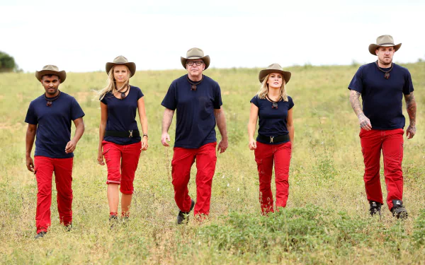 Australian cast of I'm a Celebrity: Get Me Out of Here! (AU) including Dane Swan, Natalie Bassingthwaighte, Tom Arnold, Tegan Martin, and Nazeem Hussain walking through a grassy field.