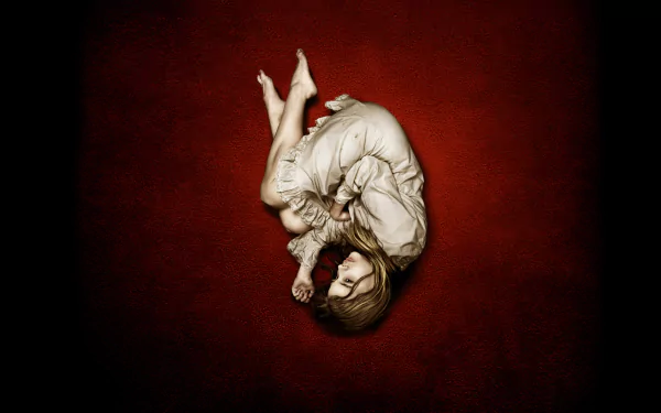 HD desktop wallpaper featuring Chloë Grace Moretz from the movie Let Me In, depicting her curled up against a deep red background.