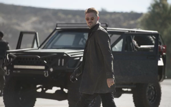 Boyd Holbrook's character from the movie Logan stands in front of a rugged vehicle, featured in a HD desktop wallpaper and background.