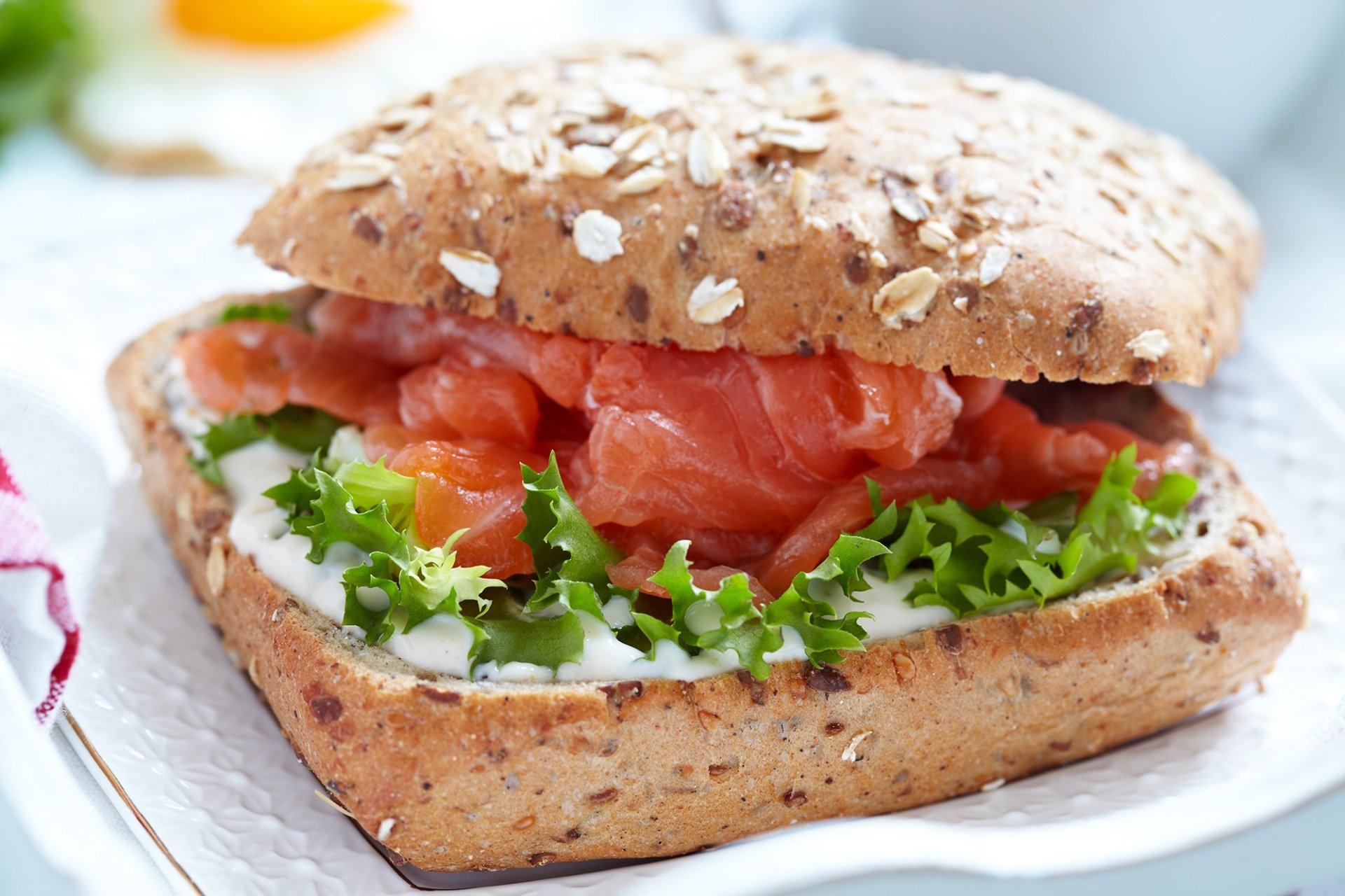 HD desktop wallpaper featuring a fresh salmon sandwich with leafy greens on multigrain bread, highlighting vibrant colors and delicious food presentation.