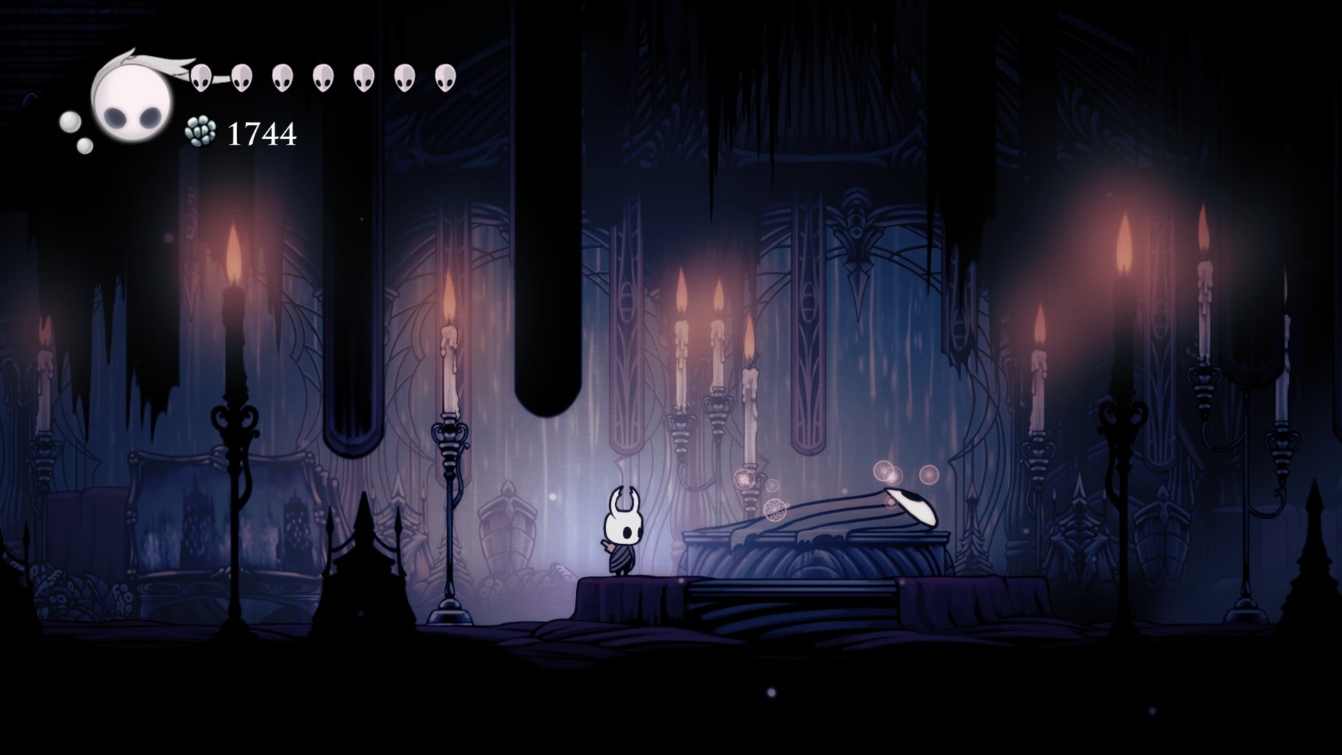 4K Ultra HD Hollow Knight video game wallpaper featuring the main character in a dark, candlelit underground setting with intricate gothic details.