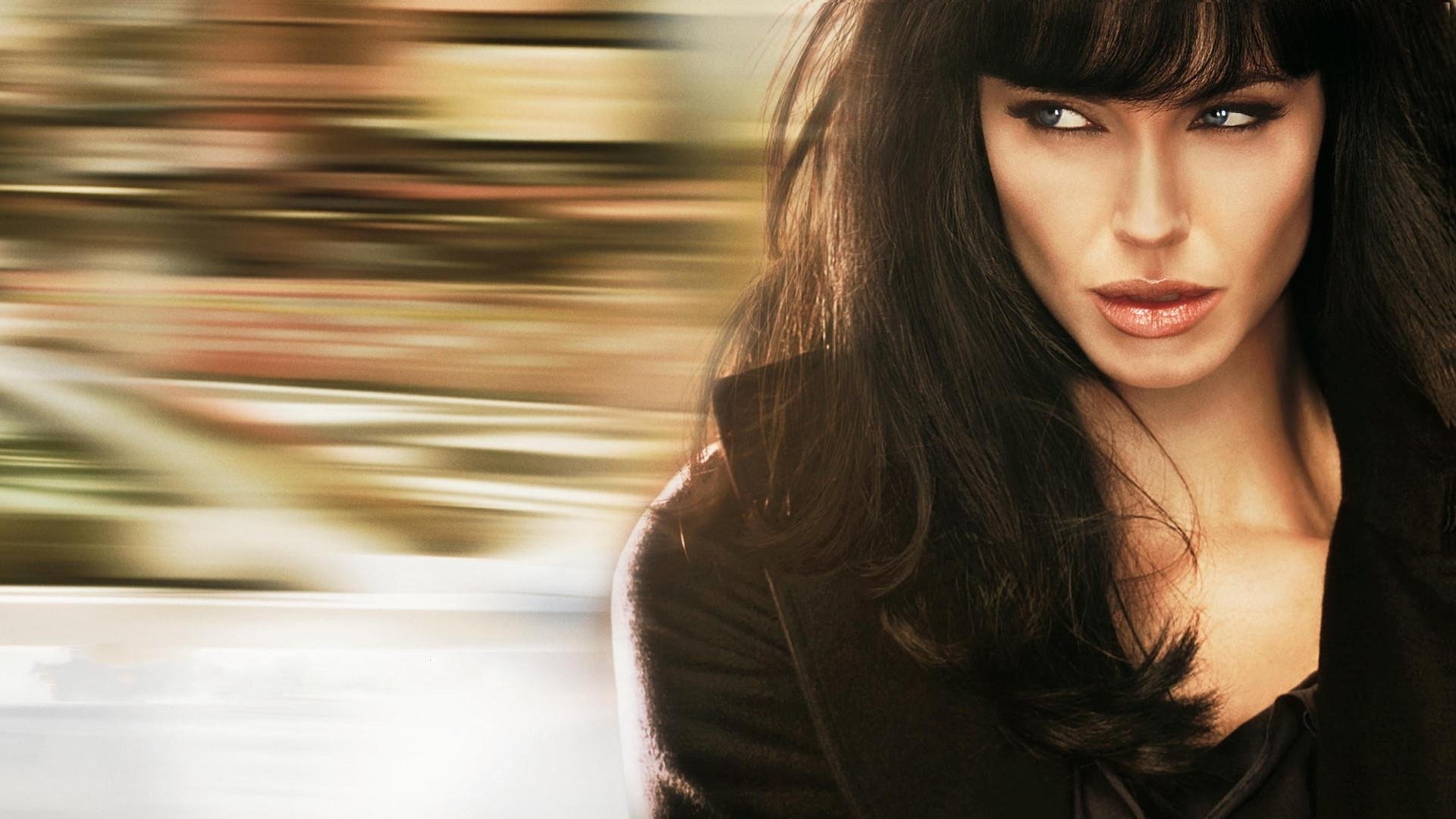 HD desktop wallpaper featuring Angelina Jolie as the lead character from the movie Salt, with a blurred motion background emphasizing her intense expression.