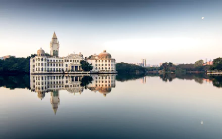 A serene view of a man-made castle building on the Pearl River in China, perfectly reflected in the calm lake waters under a clear sky.